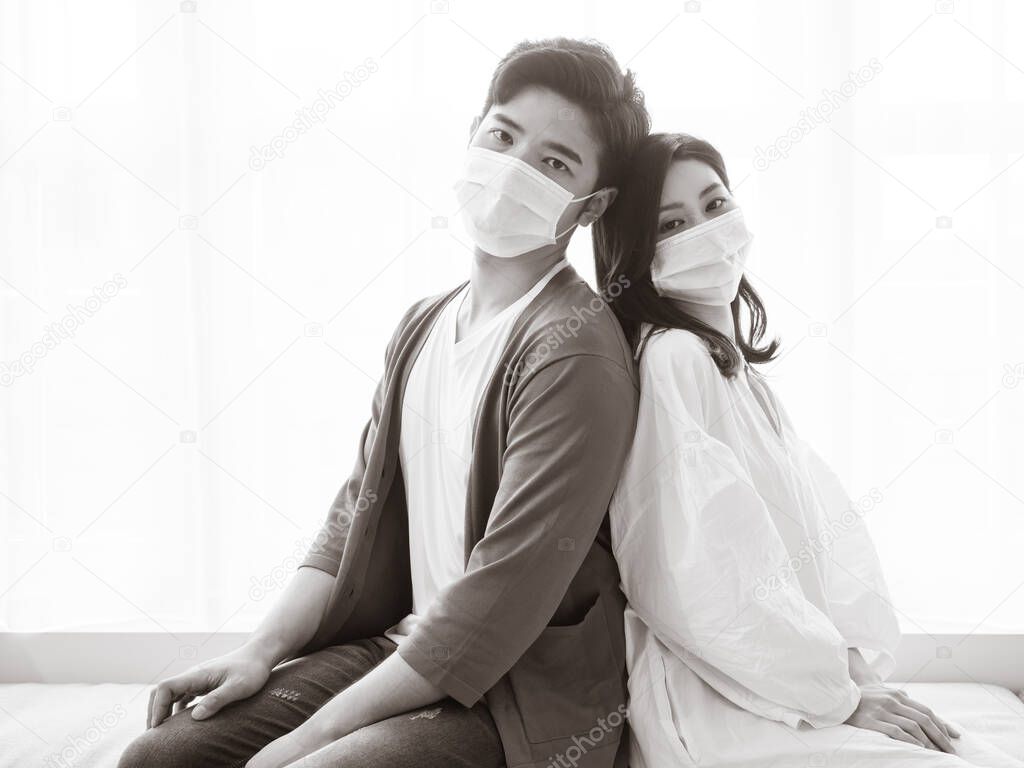 Young asian woman and man wearing Surgical mask to prevent infection at home quarantine