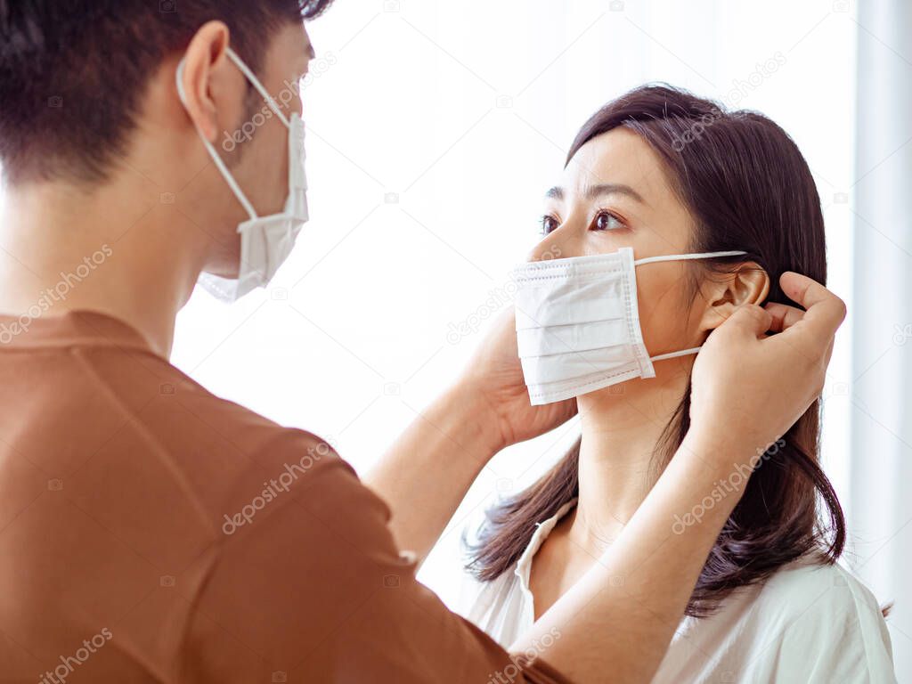 Young asian woman and man wearing Surgical mask at home