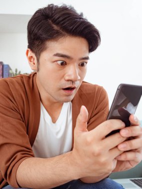 Asyalı adamın mutlu ve etkileyici yüzü akıllı telefon kullanıyor..