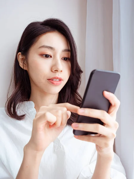 在家里用智能手机的年轻亚洲女人 — 图库照片