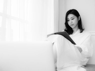 Güzel bir Asyalı kadın siyah beyaz bir kitap yazar.