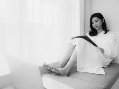 Güzel bir Asyalı kadın siyah beyaz bir kitap yazar.