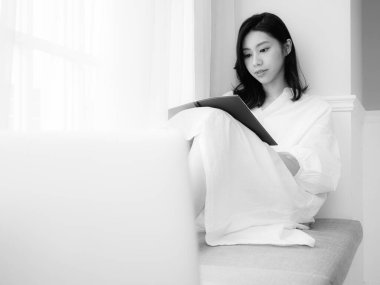 Güzel bir Asyalı kadın siyah beyaz bir kitap yazar.