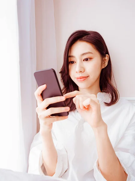 在家里用智能手机的年轻亚洲女人 — 图库照片