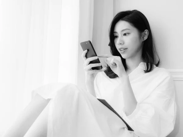 Genç Asyalı Kadın Evde Siyah Beyaz Akıllı Telefon Kullanıyor — Stok fotoğraf