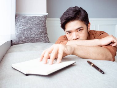 Genç Asyalı adam evde kitap okuduktan sonra ara veriyor.