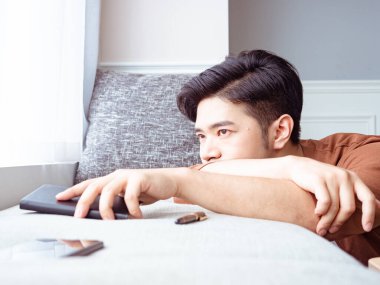 Genç Asyalı adam evde kitap okuduktan sonra ara veriyor.