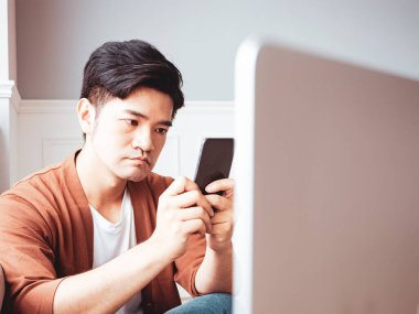 Gündelik kıyafetler giyen ve akıllı telefon kullanan genç bir adam.