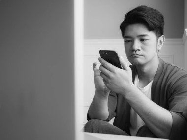 Gündelik kıyafetler giyen ve akıllı telefon kullanan genç bir adam.