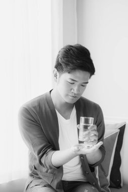 Genç Asyalı adam içeride vitamin alıyor.