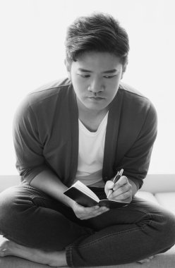 Not defterine yazı yazan çapraz bacaklı genç Asyalı..