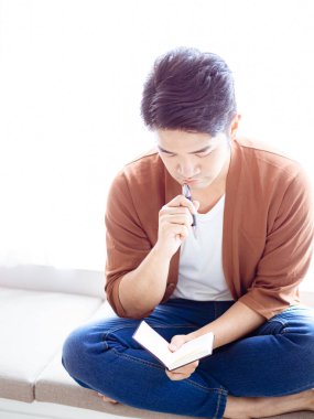 Not defterine yazı yazan çapraz bacaklı genç Asyalı..