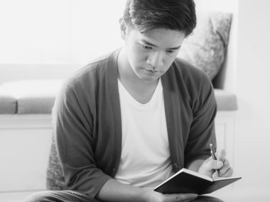 Not defterine yazı yazan çapraz bacaklı genç Asyalı..