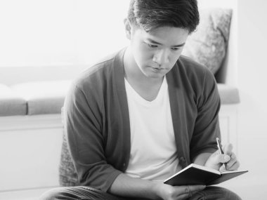 Not defterine yazı yazan çapraz bacaklı genç Asyalı..