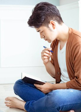 Not defterine yazı yazan çapraz bacaklı genç Asyalı..