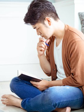 Not defterine yazı yazan çapraz bacaklı genç Asyalı..