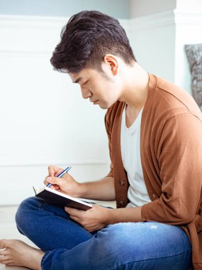 Not defterine yazı yazan çapraz bacaklı genç Asyalı..