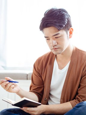 Not defterine yazı yazan çapraz bacaklı genç Asyalı..