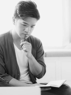 Not defterine yazan Asyalı genç adam..