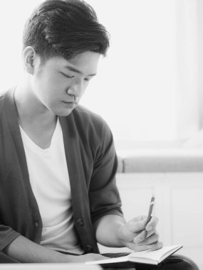 Not defterine yazan Asyalı genç adam..