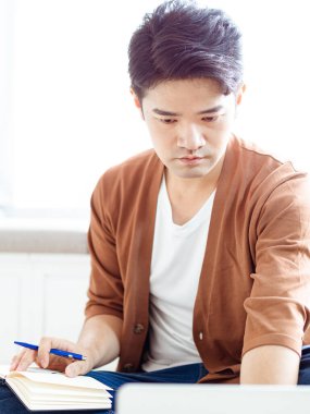 Not defterine yazan Asyalı genç adam..