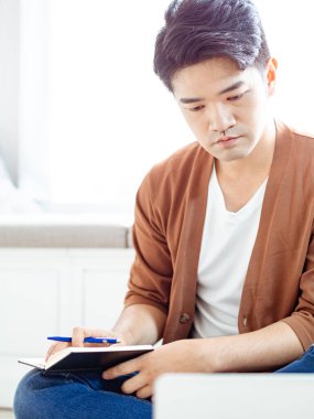 Not defterine yazan Asyalı genç adam..