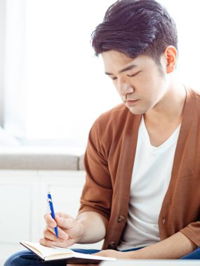 Not defterine yazan Asyalı genç adam..