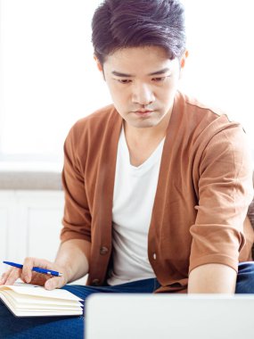 Not defterine yazan Asyalı genç adam..