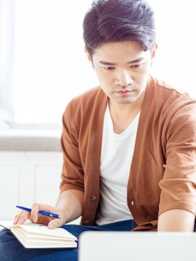 Not defterine yazan Asyalı genç adam..