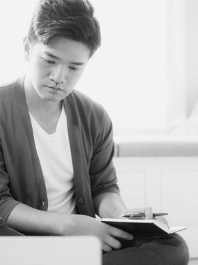 Not defterine yazan Asyalı genç adam..