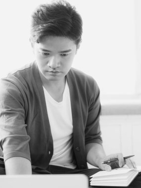 Not defterine yazan Asyalı genç adam..