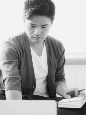 Not defterine yazan Asyalı genç adam..