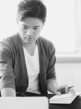 Not defterine yazan Asyalı genç adam..