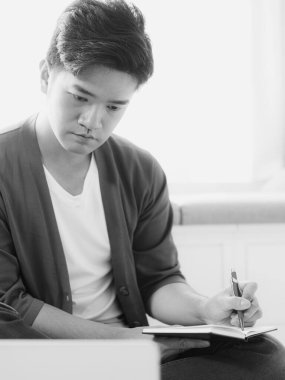 Not defterine yazan Asyalı genç adam..