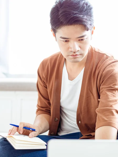 Not defterine yazan Asyalı genç adam..