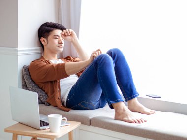 Asyalı genç adam dizüstü bilgisayar kullandıktan sonra mola verdi