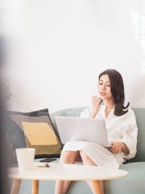 Genç Asyalı kadın evde bilgisayar kullanıyor.