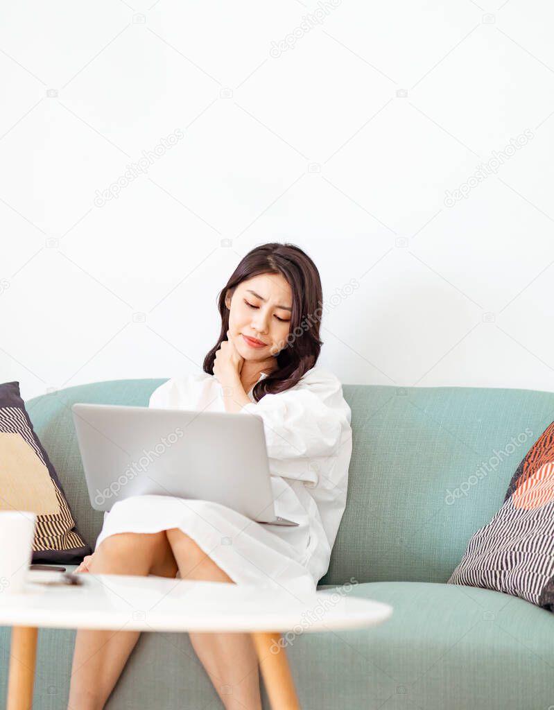 Young asian woman suffering from pain in shoulder when using laptop