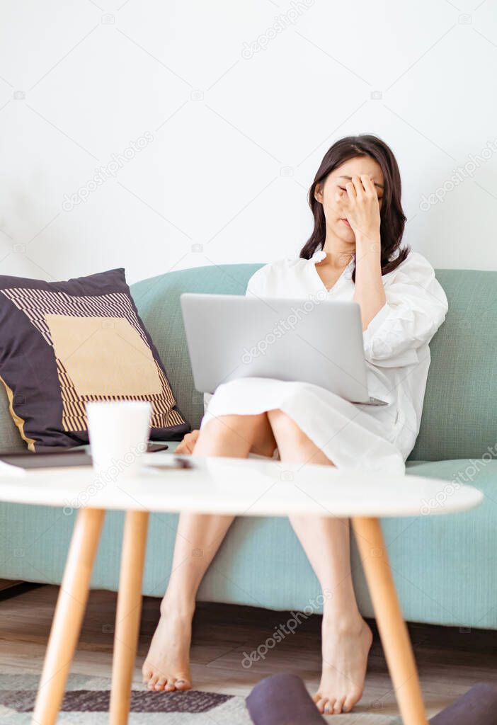 Asian young woman rubbing her tired eyes when using laptop.