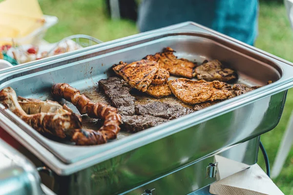 Various grilled meats (pork, chicken, beef) at a garden party in the evening — Stock Photo, Image