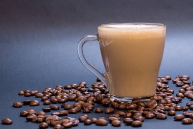 Şeffaf cam fincan kahve ve kahve çekirdekleri üzerinde mavi arka plan ile. Parlak sesi, yumuşak odak