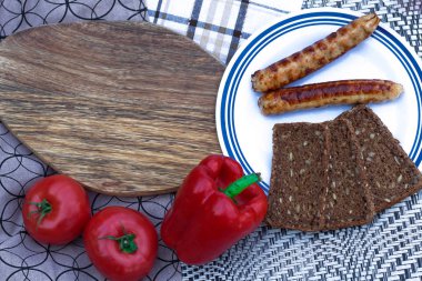 Taze sebzeli ızgara et sosisleri. İki bardak kırmızı şarap.