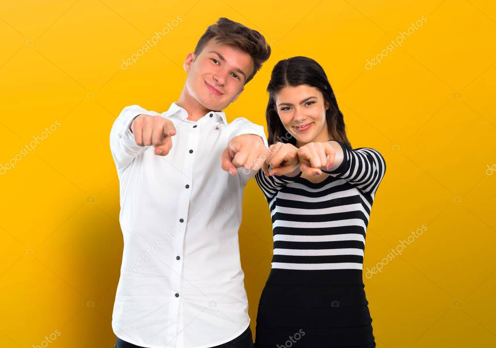 Young couple points finger at you