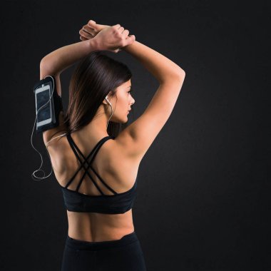 Genç kız müzik dinleme ve siyah arka plan üzerine germe spor