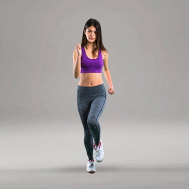 Gri arka plan üzerinde koşan genç spor kız
