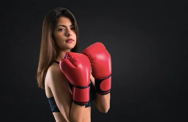 Young sport girl with boxing gloves on black background