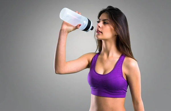 Jeune Fille Sportive Avec Une Bouteille Sur Fond Gris — Photo