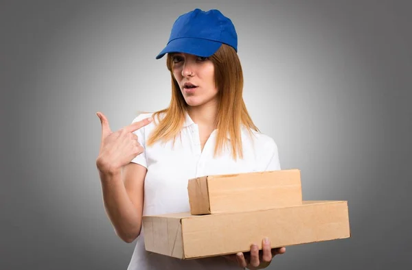 Delivery woman making surprise gesture on grey background