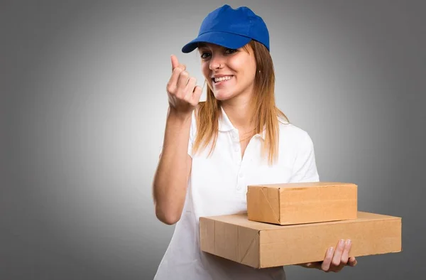 Delivery woman making money gesture on grey background