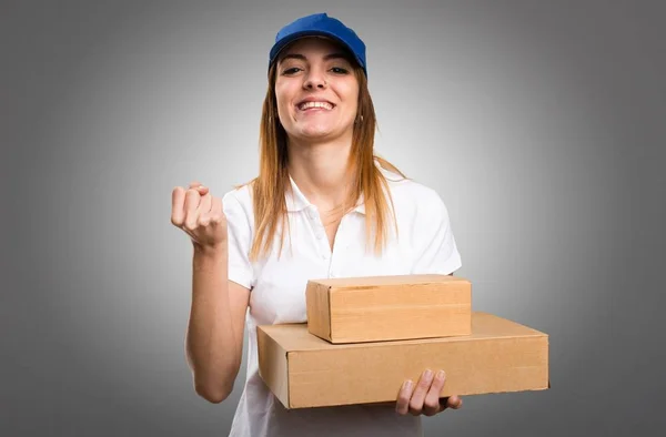 Lucky delivery woman on grey background